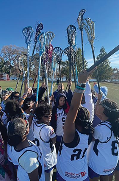 Harlem Lacrosse team in a huddle on the field